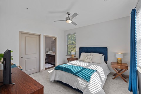 A bedroom with a bed, a ceiling fan, and a television.