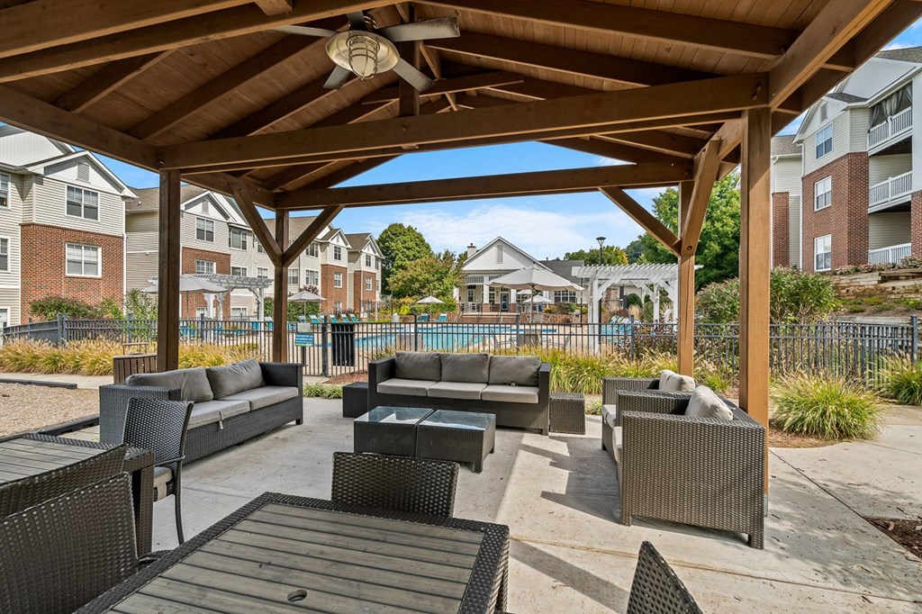 an outdoor patio with tables and chairs under a wooden pavilion