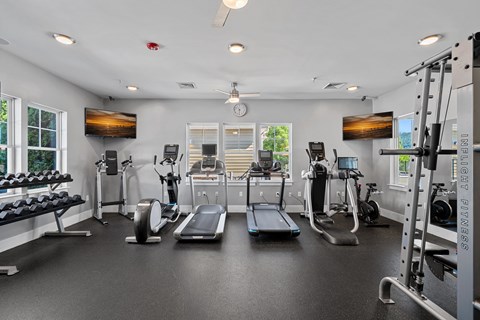A spacious gym with a variety of equipment including treadmills, elliptical machines, and weight machines.