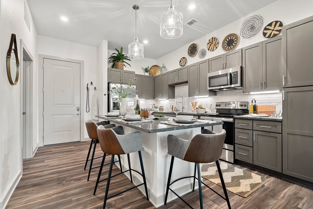 a kitchen with gray cabinets and a white island with chairs