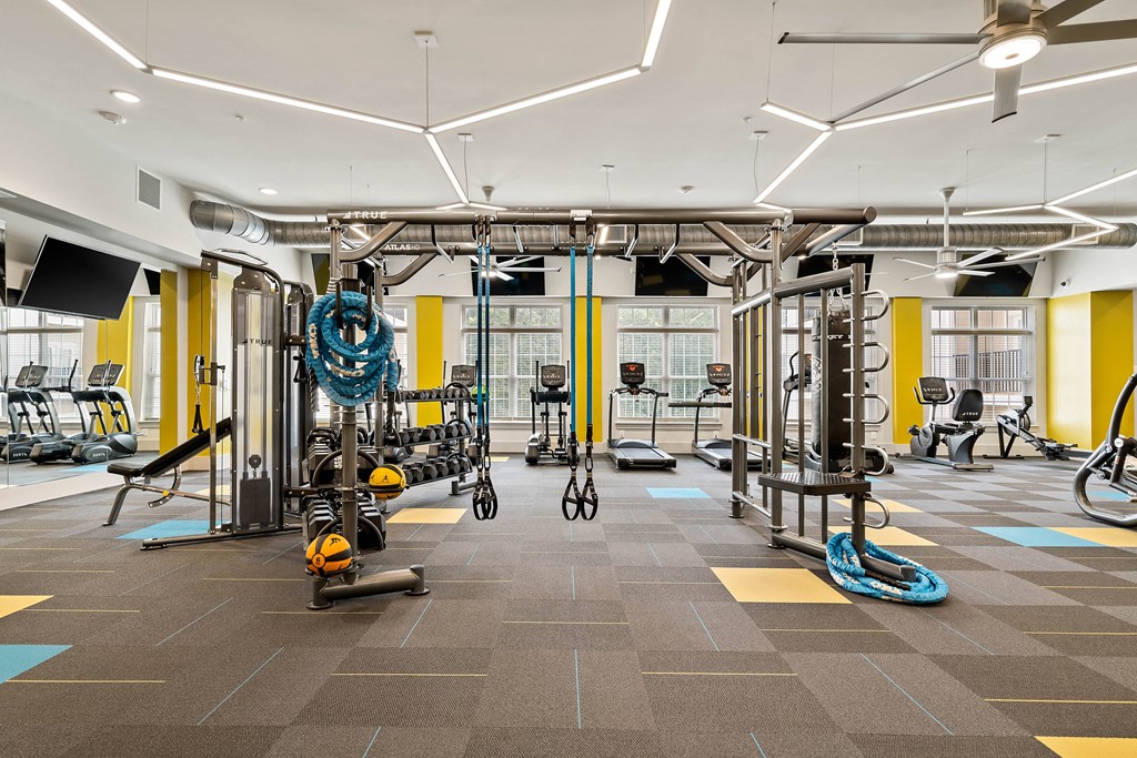 a gym with weights and cardio equipment in a building with windows