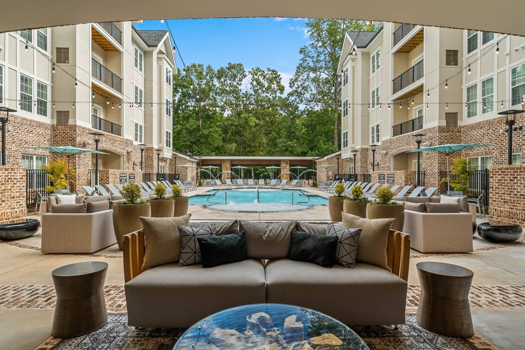 a clubhouse with a pool and apartments in the background