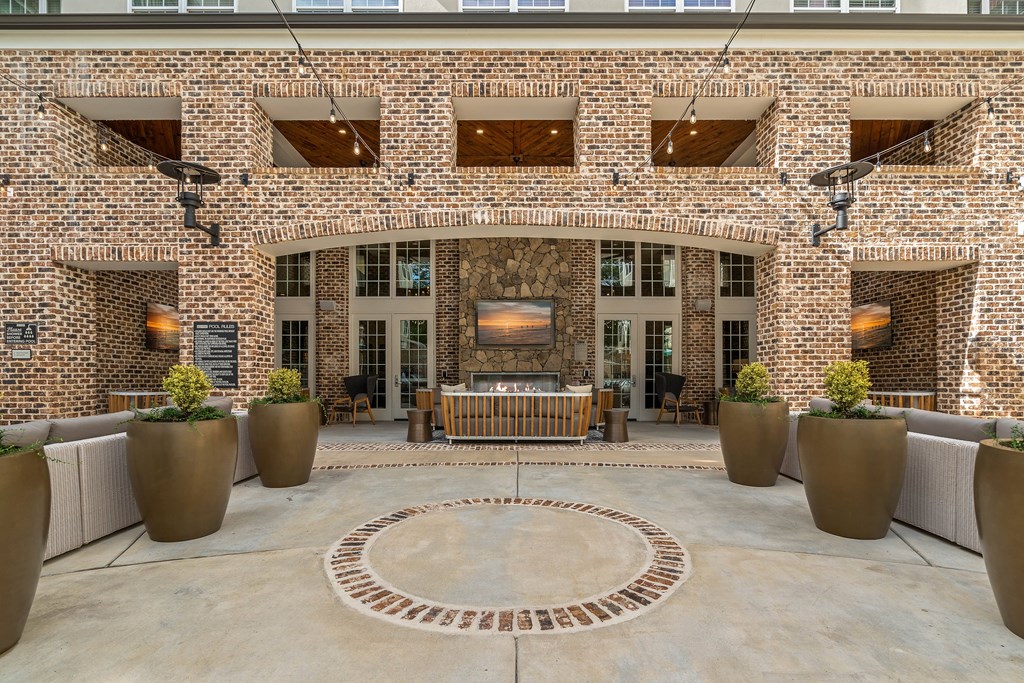 the courtyard of a brick building with a seating area and a fireplace