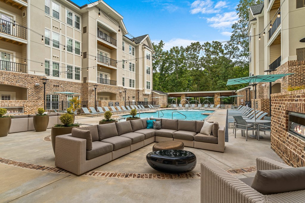 a clubhouse with a pool and furniture in front of an apartment building
