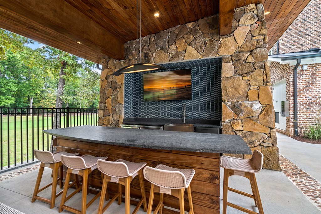 an outdoor bar with stools and a television on the wall