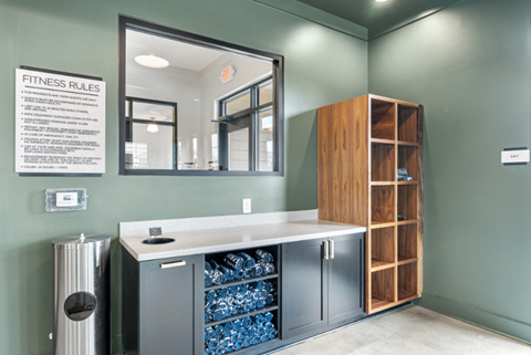 a fitness room with a large mirror and a storage cabinet with bottled water
