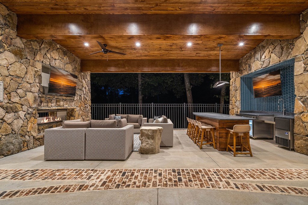 a covered patio with couches and a bar and a grill