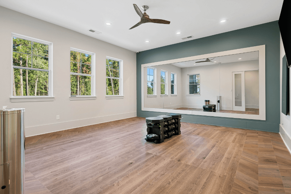 an empty living room with a large mirror and a ceiling fan