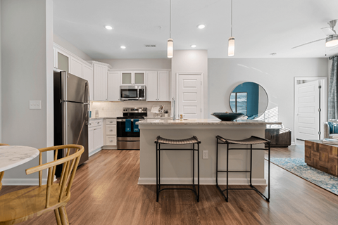 a kitchen with white cabinets and a large island with two stools
