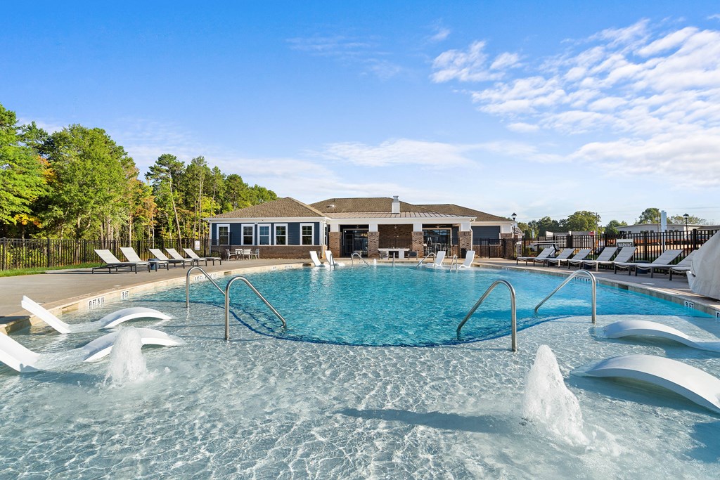 a large pool with chairs and a building in the background