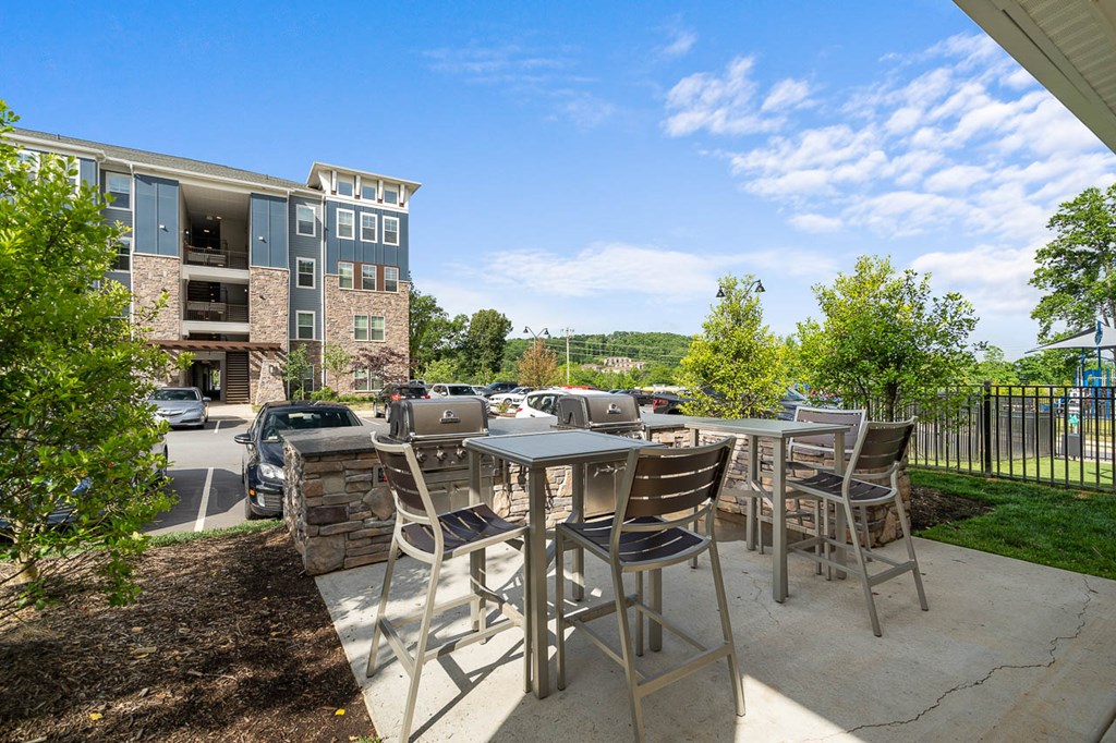 a patio with tables and chairs and a building in the background