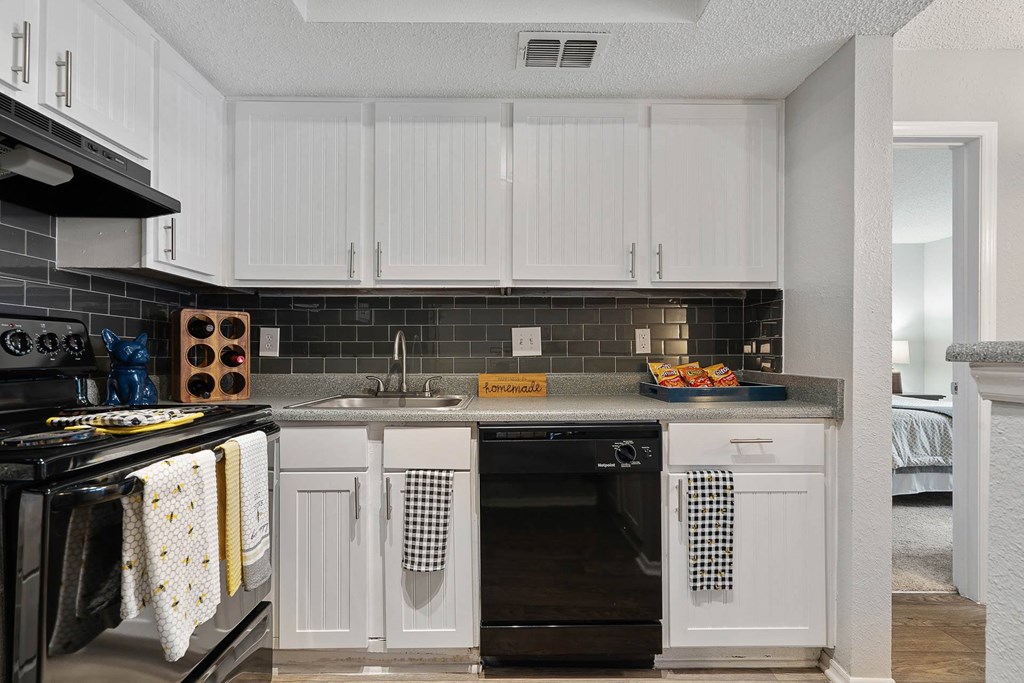 a kitchen with white cabinets and black appliances