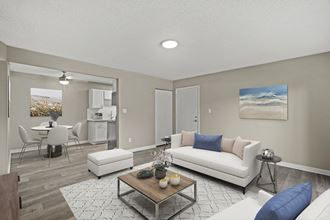 a living room with a couch coffee table and a dining room table in the background