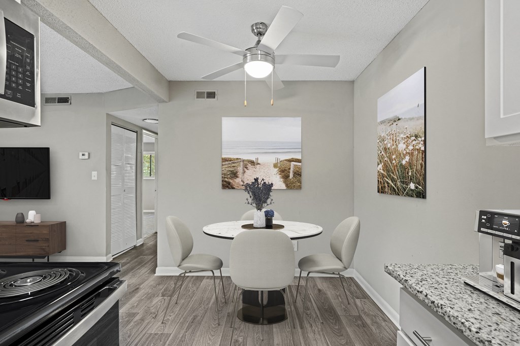a dining area with a table and chairs and a ceiling fan