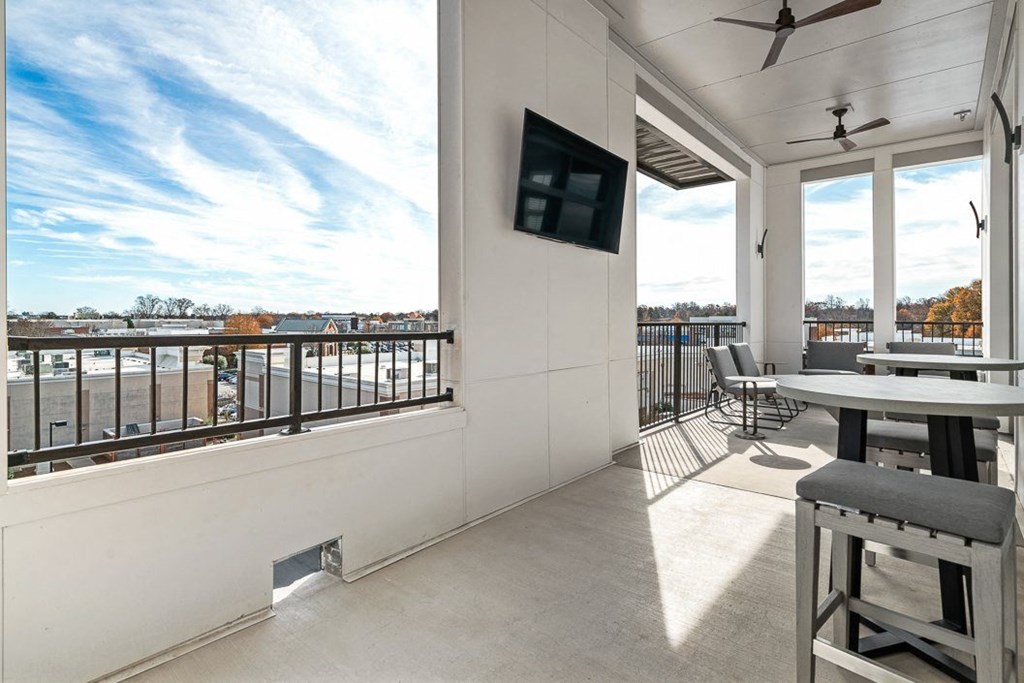 a balcony with tables and chairs and a tv on the wall