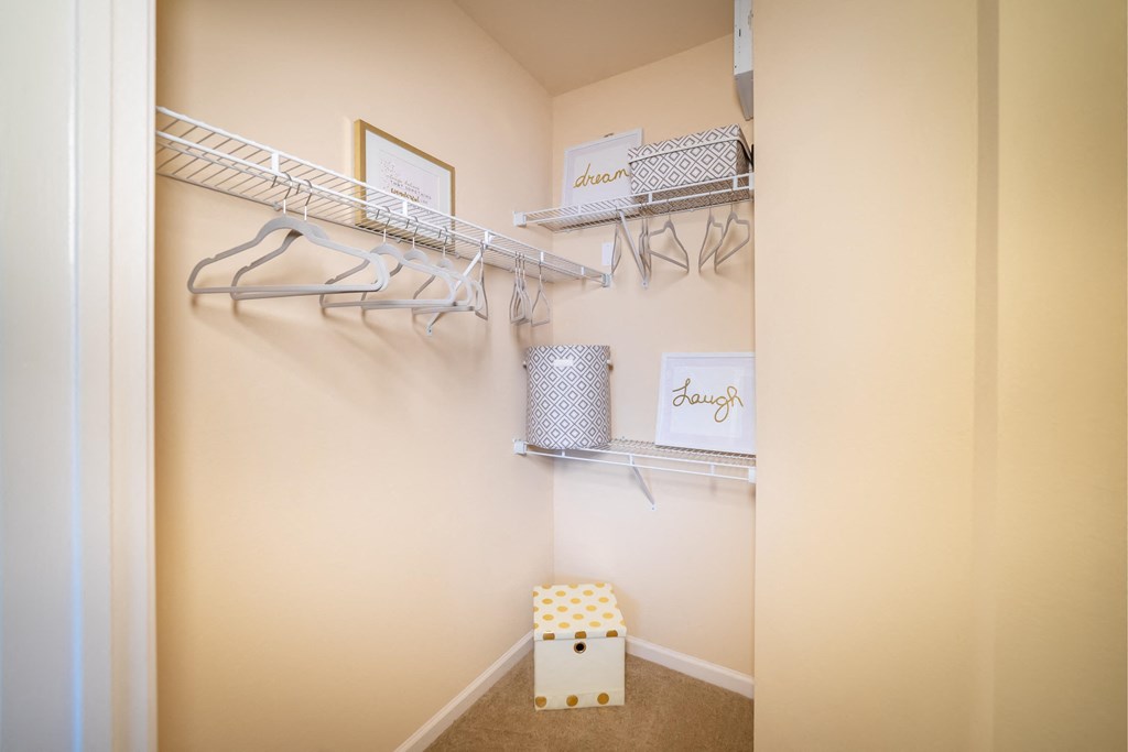 a walk in closet with shelves and a stool in it