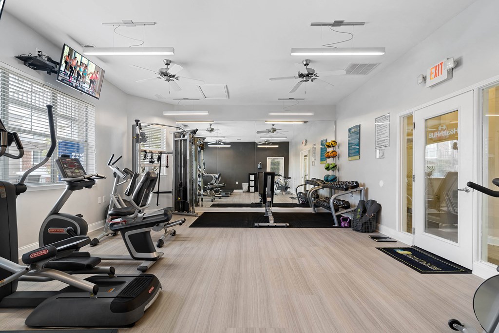 a gym with treadmills and other exercise equipment on a wooden floor