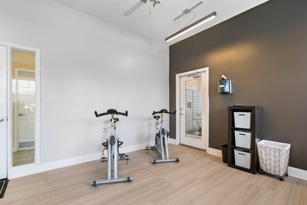 a fitness room with two bikes and a mirror