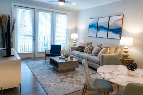 A living room with a sofa, chairs, and a painting on the wall.