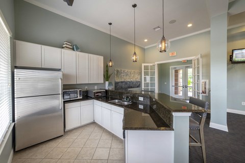 a kitchen with white cabinets and granite counter tops and a stainless steel refrigerator
