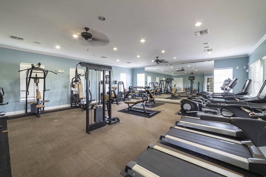 a gym with treadmills and other exercise equipment on a wood floor