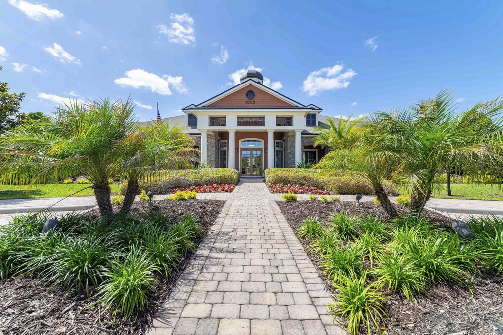 a house with a pathway and palm trees in front of it