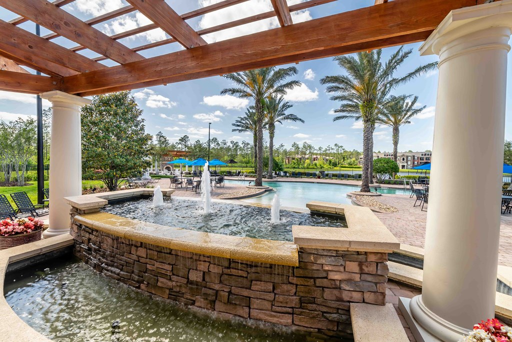 a resort style pool with a water feature and palm trees