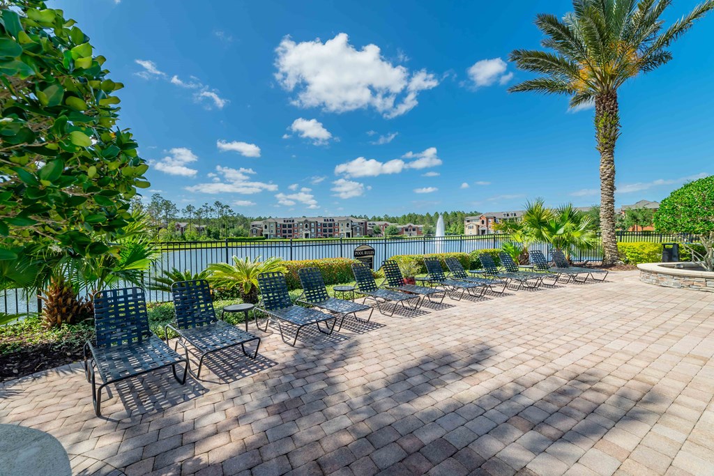 a patio with blue chairs and a lake in the background