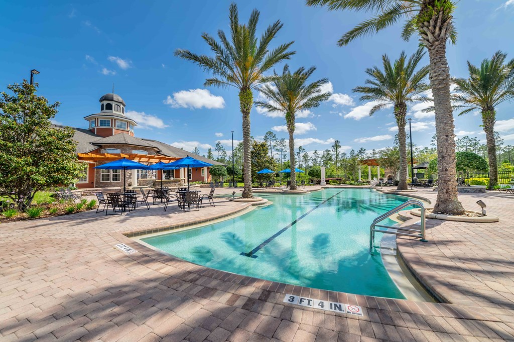 a swimming pool with palm trees and a building in the background