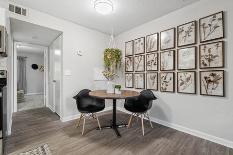 a dining room with pictures on the wall and a table with two chairs