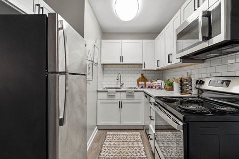 a kitchen with white cabinets and black appliances and a refrigerator