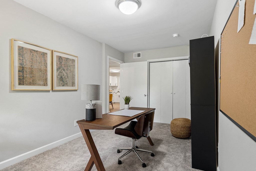 a home office with a desk and a door to a bathroom
