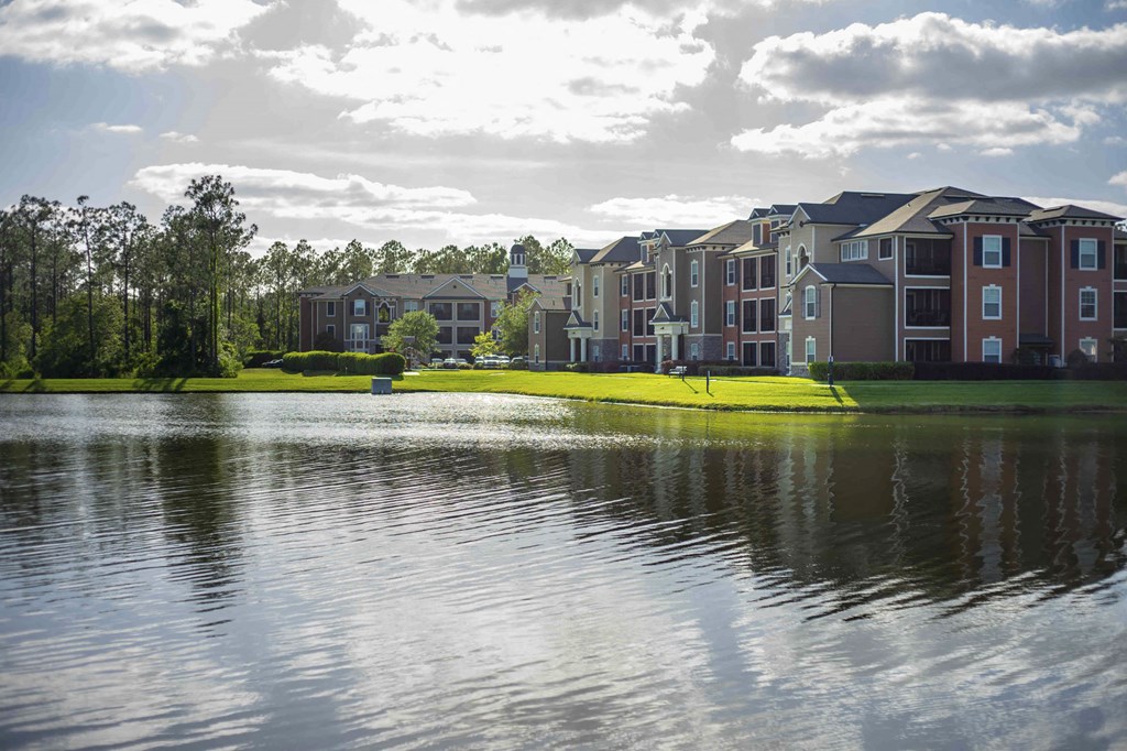 a row of houses on a field with a reflection of a city in the water