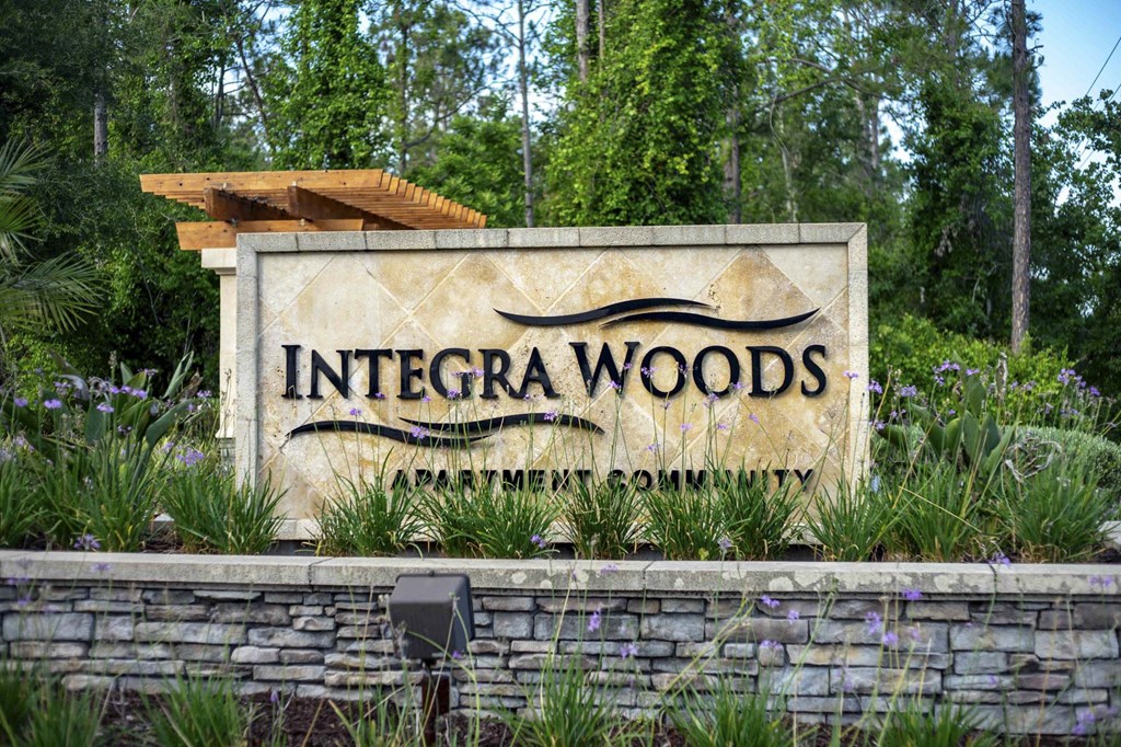 a sign for integra woods in front of a forest