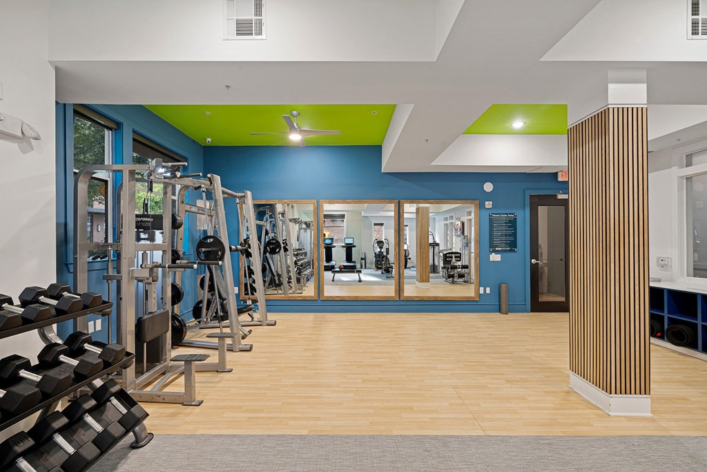 a gym with cardio machines and weights on the floor and a blue and green wall