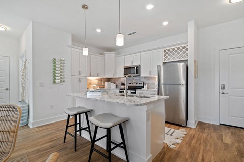 A kitchen with a white island and bar stools.