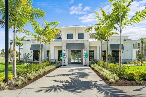 A white building with a green sign in front of it.