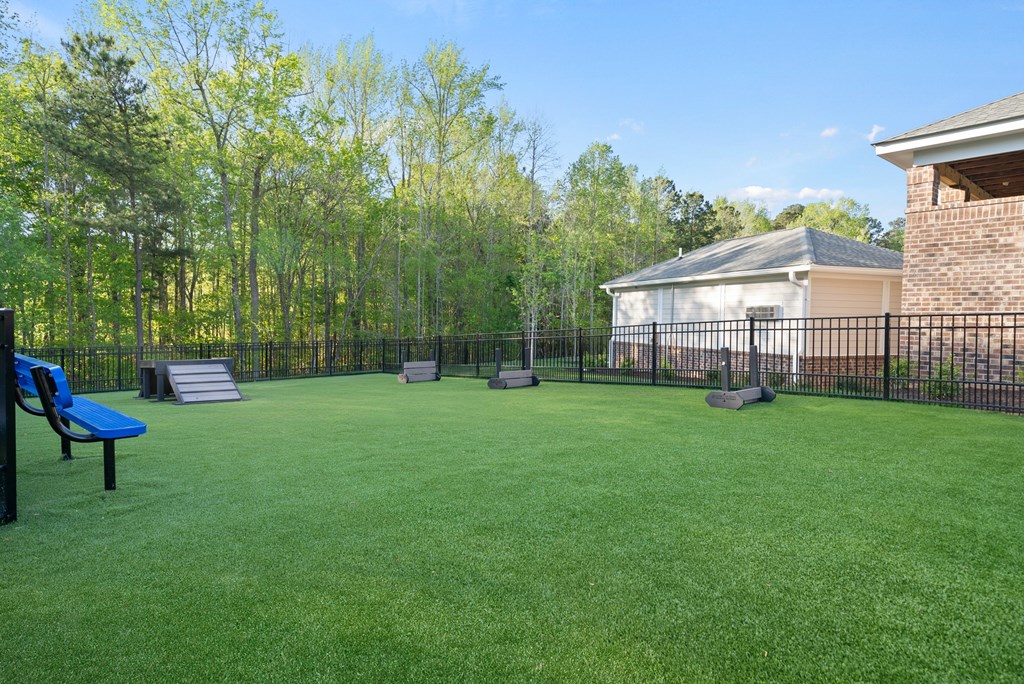 A backyard with a green lawn and a blue bench.