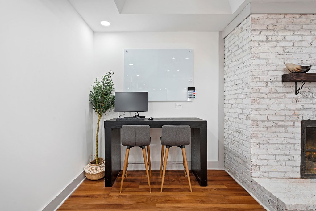 a desk with two chairs in a room with a fireplace and a tv