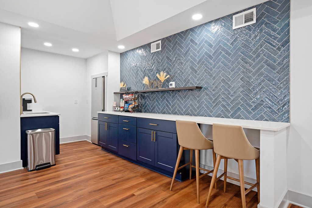 a kitchen with blue cabinets and a counter with two chairs