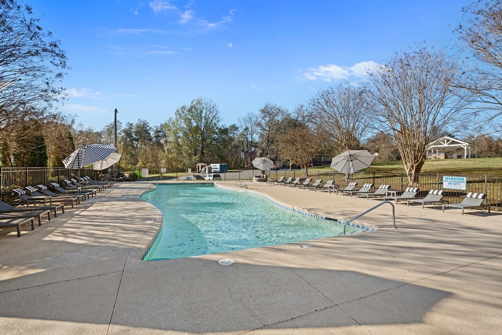 a swimming pool with chaise lounge chairs and trees