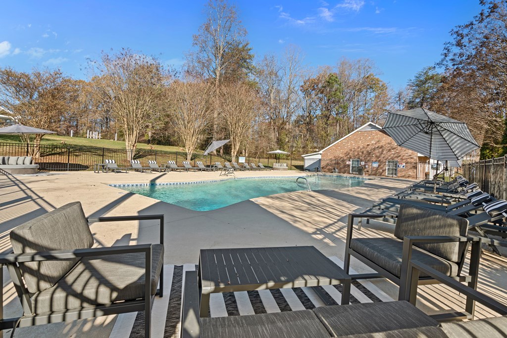 a pool with chairs and an umbrella next to a resort style pool