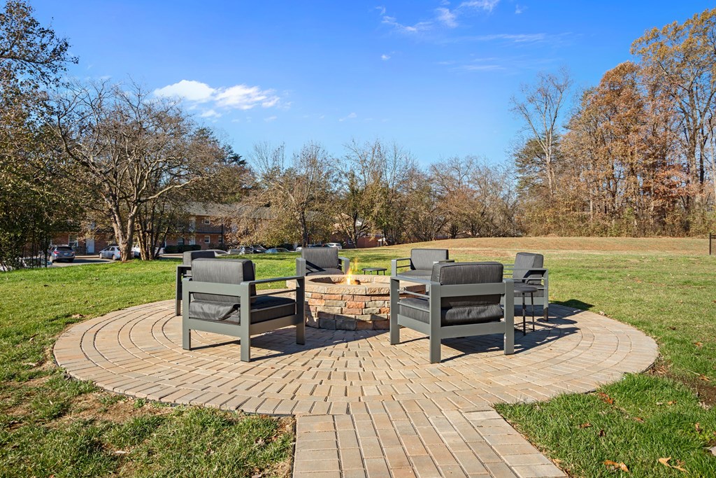 a patio with chairs and a fire pit in a park