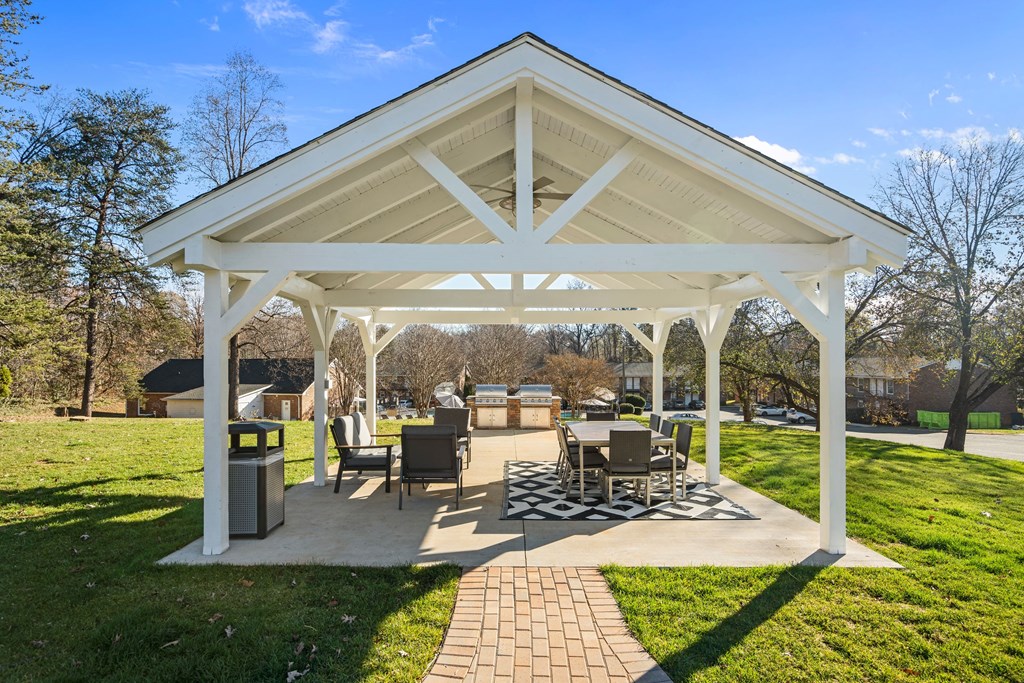 a pavilion with a table and chairs in a park