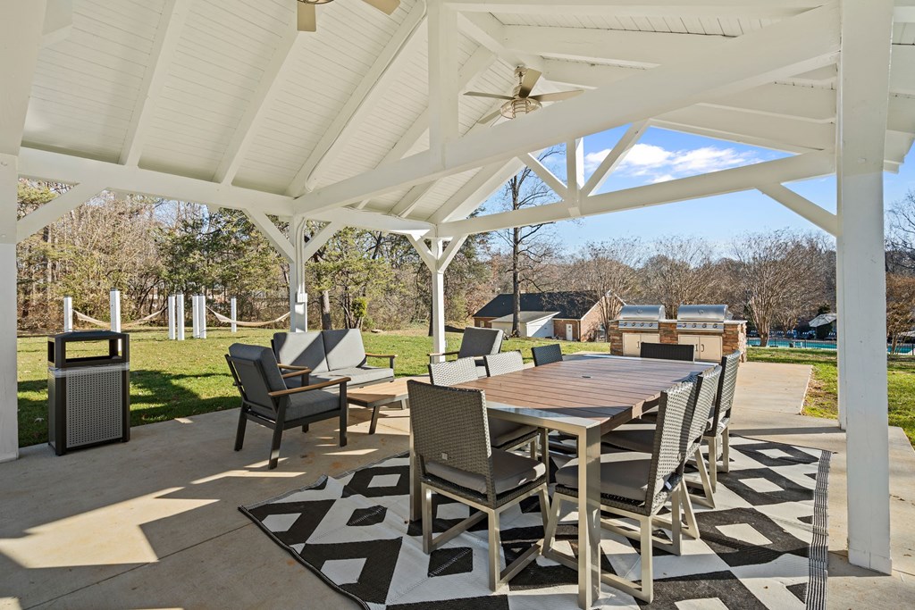 a patio with a table and chairs and a grill
