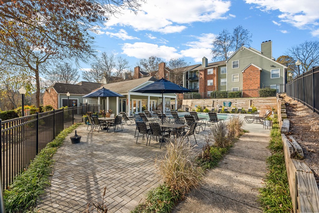 a patio with tables and chairs in front of a house