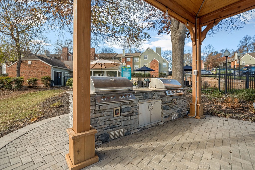 a stone outdoor kitchen with a grill and a patio