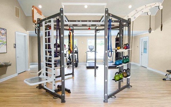 a gym with weights and equipment in a room with a wooden floor