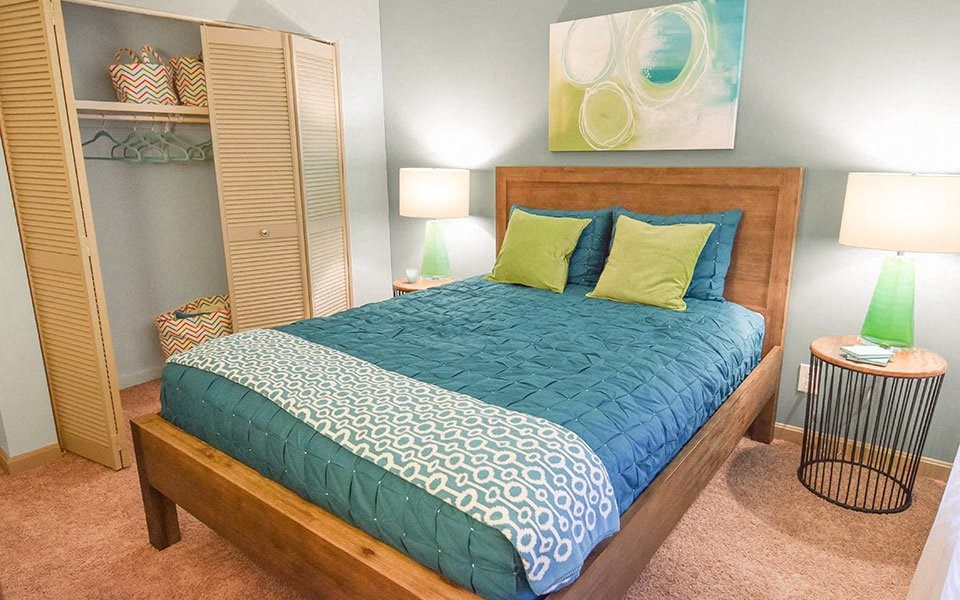 a bedroom with a bed with blue and green pillows
