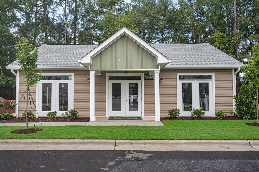 the front of a house with a lawn and trees